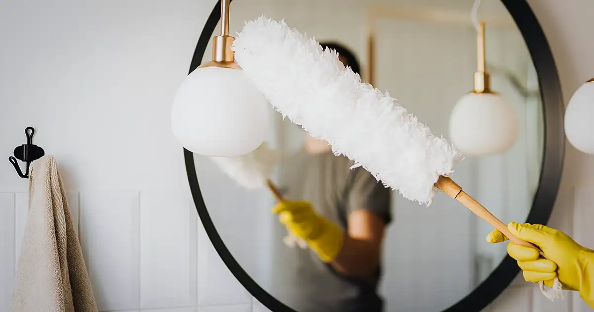 Homeowner using a feather duster to attempt to keep house free of dust.