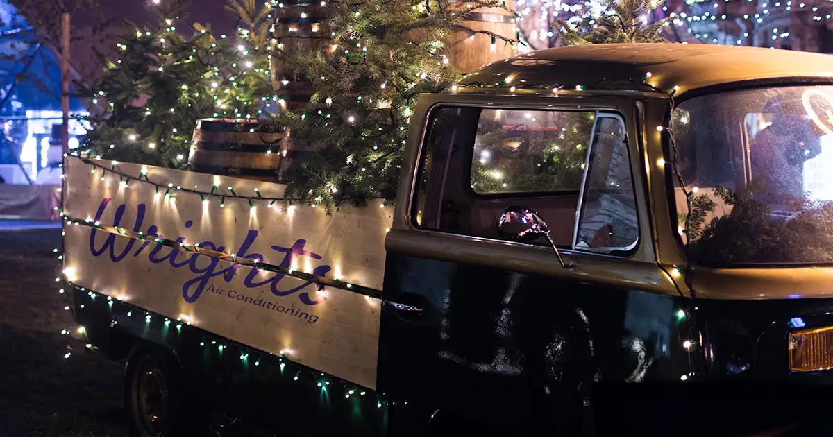 An old fashion truck carrying a Christmas tree, and it's all adorned in holiday lights.