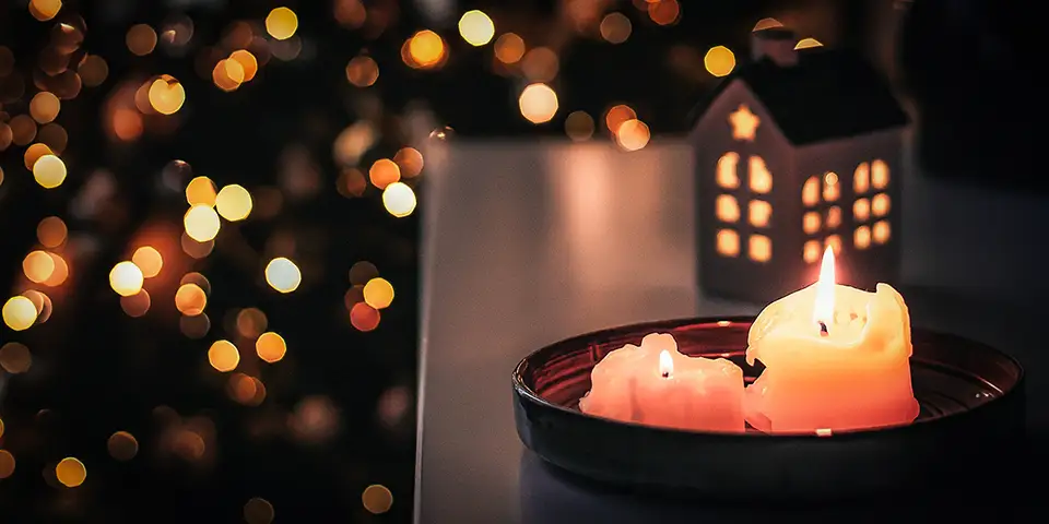 Candle burning, with Christmas tree in the background.