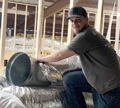 A Wright's Air Conditioning tech installing ductwork in a commercial building.
